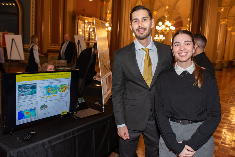 Vanessa and Santiago pose by their digital poster